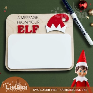 May include: A wooden sign with the text "A MESSAGE FROM YOUR ELF" in red letters. The sign includes a white dry-erase board and a red and white elf hat. A black marker and an elf doll are also visible.