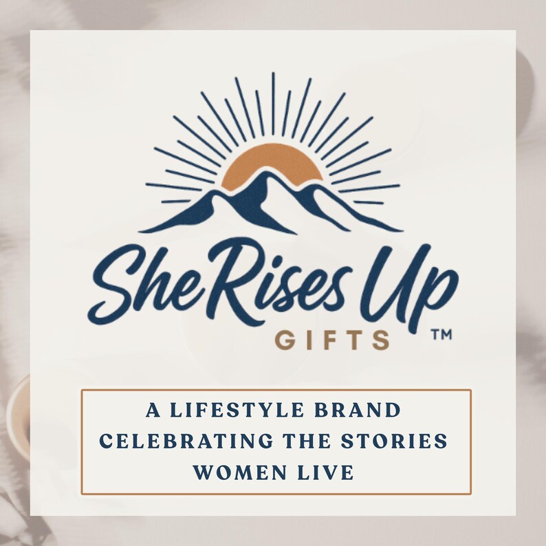 May include: A logo featuring a dark blue mountain range silhouette beneath a semi-circular orange sun with radiating lines. The text reads She Rises Up GIFTS, followed by a box containing the text A LIFESTYLE BRAND CELEBRATING THE STORIES WOMEN LIVE.