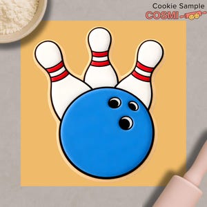 May include: A cookie cutter shaped like a bowling ball and pins. The bowling ball is blue with three black holes. The pins are white with red stripes. The cookie cutter is on a yellow background. Text in the upper right corner reads "Cookie Sample COSIMI".