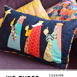 May include: A rectangular cushion with a navy blue background featuring an applique design of the Three Wise Men. The figures are adorned in colorful patchwork fabrics, holding lanterns. The text "WE THREE KINGS" is at the bottom.
