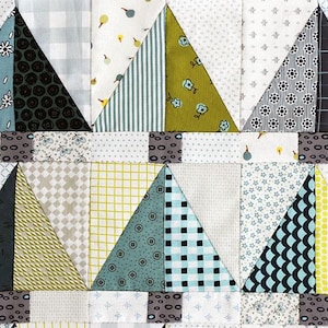 May include: A patchwork quilt with a geometric pattern of triangles in shades of blue, green, yellow, and gray. The triangles are arranged in rows and columns, creating a visually appealing design.