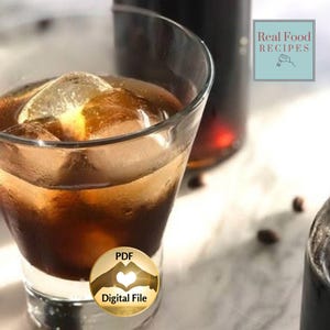 May include: A clear glass filled with a dark brown liquid and ice cubes. A dark bottle is in the background. The image also includes the text "Real Food Recipes" and "PDF Digital File".