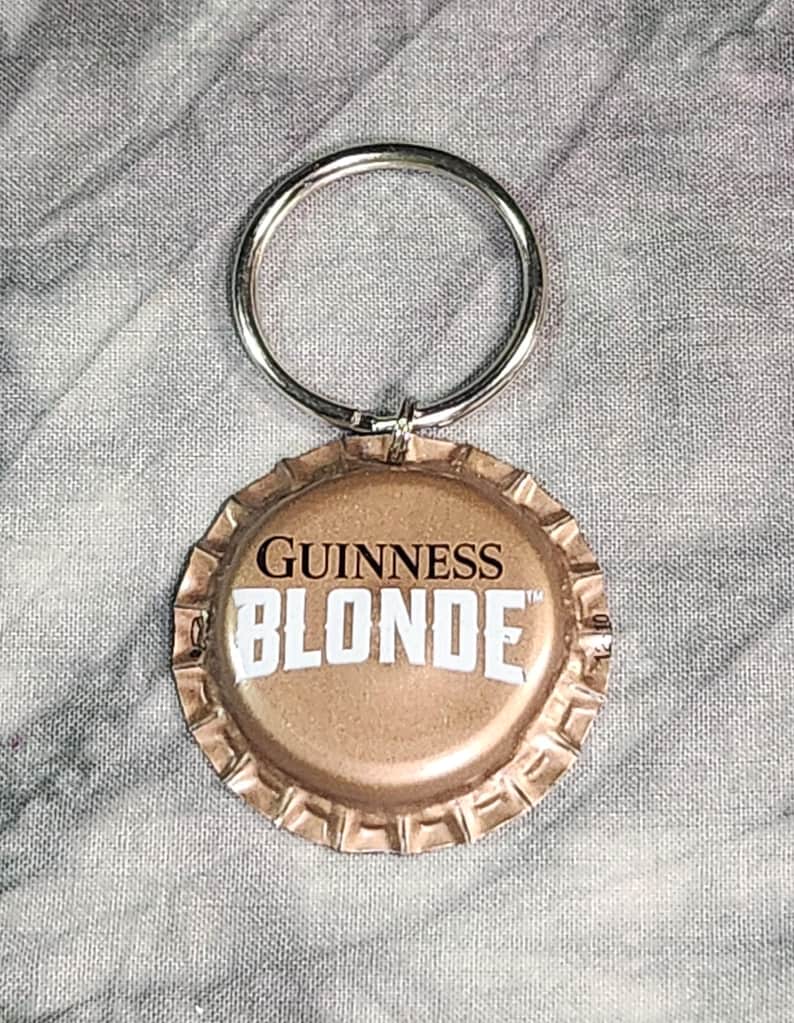 Pu&ograve; includere: Un portachiavi con un tappo di bottiglia di birra Guinness Blonde. Il tappo &egrave; color oro con le parole "GUINNESS BLONDE" in bianco. Un anello di metallo argentato &egrave; attaccato per le chiavi.