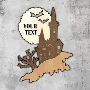 Puede incluir: Un recorte de madera de una casa encantada espeluznante con murciélagos volando alrededor de una luna llena. La luna tiene el texto "YOUR TEXT" en ella.