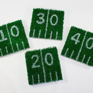 May include: Four green and white felt football field yard markers. The markers are numbered 10, 20, 30, and 40.