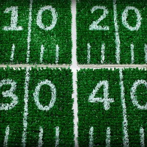 May include: Four green squares with white numbers 10, 20, 30, and 40 painted on them. The squares are made of artificial turf.