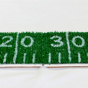 May include: A green and white football field rug with the numbers 10, 20, 30, and 40 printed on it.
