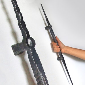 May include: Black metal door handle with a long, pointed design. The handle has a textured surface and a rounded end.