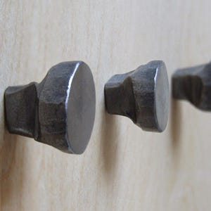 May include: Three metal cabinet knobs with a hammered finish. The knobs are round and have a slightly pointed base.