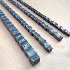 May include: Four metal rods with a textured, wavy surface. The rods are arranged in a row, with the longest rod at the top and the shortest rod at the bottom.