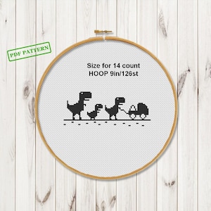 May include: A cross-stitch hoop with a black and white dinosaur family design. The text on the design reads "Size for 14 count HOOP 9in/126st". The hoop is 9 inches in diameter.