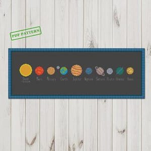 May include: A cross-stitch pattern of the solar system, featuring the sun and planets in various colors against a dark gray background. The planets are labeled with their names. The design is framed in a blue plaid border, with "PDF PATTERN" in a green stamp.
