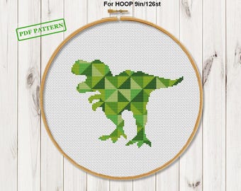 May include: A cross-stitch pattern featuring a green geometric Tyrannosaurus Rex design. The design is set within a wooden embroidery hoop. Text on the image reads "PDF PATTERN" and "Size for 14 count For HOOP 9in/126st".