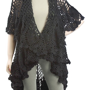 Puede incluir: Chaleco de crochet negro con un dobladillo festoneado y un profundo escote en V. El chal está hecho de una tela ligera y de tejido abierto.