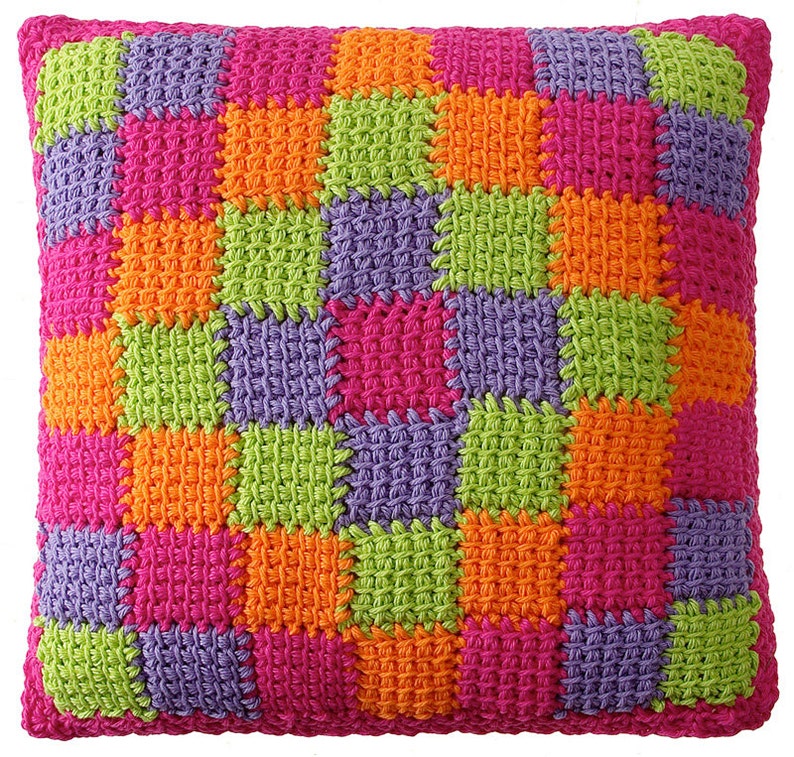 May include: A square crocheted pillow with a colorful patchwork design. The pillow is made of squares in pink, purple, green, and orange.