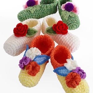 May include: Six pairs of crocheted baby shoes with floral embellishments. The shoes are in various colors, including green, white, pink, orange, and yellow. Each shoe features a different flower design, with some having leaves.