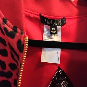 May include: A red bomber jacket with a black leopard print pattern. The jacket has a gold zipper and a red lining. The tag reads "IMAN" and "1X".