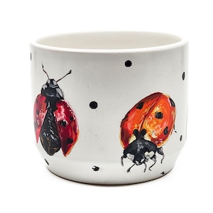 May include: A set of three ceramic mugs with a speckled, matte finish. The mugs are in shades of cream, light gray, and dark gray. Each mug has a simple, minimalist design and a rounded handle. The mugs are likely for coffee or tea.