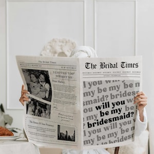 May include: A person holding a newspaper titled "The Bridal Times" with the headline "Will you be my bridesmaid?" The newspaper features wedding-related articles and photos. A croissant and a glass of water are on the table.