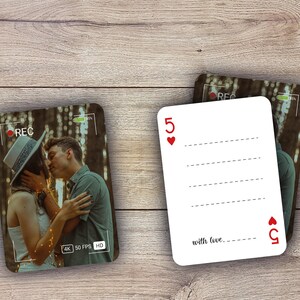 May include: Two playing cards with a romantic theme. One card features a photo of a couple kissing, with a 'REC' recording overlay. The other card is a white playing card with the number 5 and the words 'with love'.