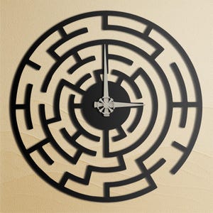 May include: A black, circular wall clock with a maze-like design. The clock face is black with silver hands and a silver center. The clock is mounted on a light beige surface.