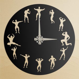 May include: A black wall clock with a circular face. The clock features cut-out silhouettes of weightlifters in place of numbers. The clock hands are silver. The background is a light beige color.