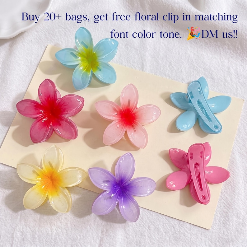 May include: A collection of six flower-shaped hair clips in various colors including blue, pink, yellow, and purple. The clips feature five petals with a gradient color effect. Two clips are shown from the back, revealing the metal snap-clip mechanism.