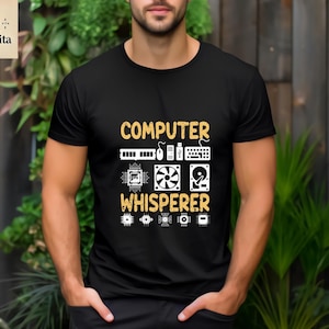 May include: Black t-shirt with the text "COMPUTER WHISPERER" in yellow. The text is surrounded by small white computer icons.