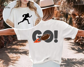 May include: White t-shirt featuring a black silhouette of a football player running with the ball. The back of the shirt displays the word "GO!" with a football and flame graphic. A casual, sporty design.