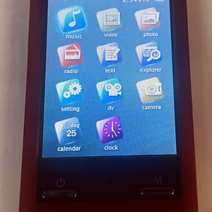 May include: A burgundy-colored digital media player with a touch screen displaying various app icons, including music, video, and calendar. The screen shows the time as 2:34 PM and the date as Friday, the 25th.