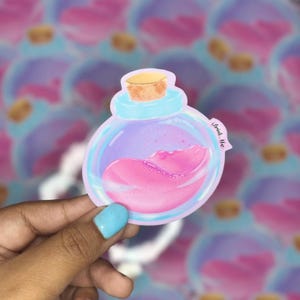 May include: A sticker of a cartoon potion bottle with a cork stopper. The bottle contains pink liquid and has a light blue and purple gradient. The text "Drink Me" is on the bottle. The background is a blurred pattern of similar bottles.