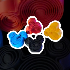 May include: Three dimensional Mickey Mouse head shapes made of paper, in blue, red, and yellow. Each shape is made of concentric circles.