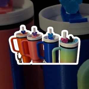 May include: Four colorful travel mugs with lids and straws. The mugs are orange, pink, blue, and green. Each mug has a different colored Mickey Mouse head on top of the lid.