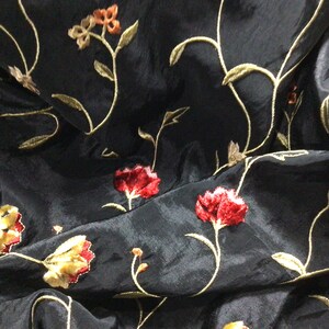 May include: Black fabric with embroidered floral design featuring red, yellow, and green flowers.