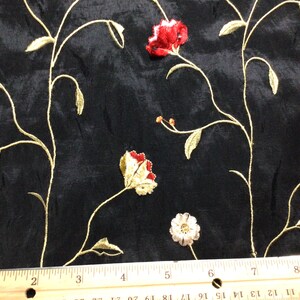 May include: Black fabric with an embroidered floral pattern in red, gold, and white. The fabric is shown with a ruler for scale.