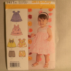 May include: A Simplicity sewing pattern for making girls' dresses and shorts. The pattern includes five different styles, all with a floral theme. The pattern number is 14/1A. The pattern is for sizes XXP-G.