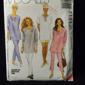 May include: A sewing pattern for a tunic top with a lace-up neckline. The pattern includes three different views of the top, each in a different color: light blue, gray, and pink. The pattern is for sizes X-Small, Small, and Medium.