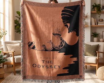 May include: A woven throw blanket in terracotta and black featuring a Greek key border. The design depicts a ship on stylized waves, a vase, and a large profile silhouette. The text reads "HOMER THE ODYSSEY" in a clean, dark sans-serif font.