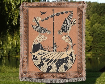 May include: A woven throw blanket featuring a tan background with a black graphic illustration of an ancient ship at sea, flanked by two large birds. The design includes a Greek key border pattern and fringed edges on the top and bottom sides.