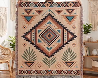 May include: A rectangular woven throw blanket featuring a large central diamond pattern in shades of tan, brown, black, and teal. The design includes geometric shapes, triangles, and stylized plant motifs with fringed edges on the top and bottom.