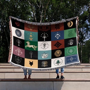 Lord of the Rings flags throw blanket displayed on stone steps, colorful magical emblems design with fringe, mythical creatures and symbols patchwork pattern
