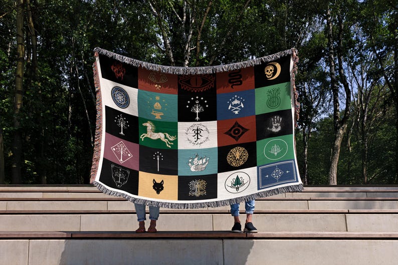 Lord of the Rings flags throw blanket displayed on stone steps, colorful magical emblems design with fringe, mythical creatures and symbols patchwork pattern