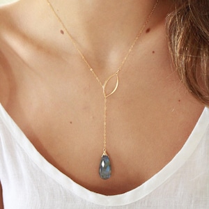 May include: A gold chain necklace with a delicate leaf pendant and a teardrop-shaped blue gemstone.