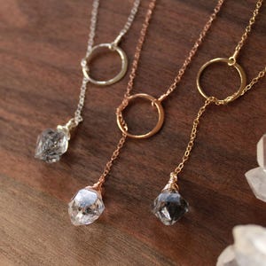Puede incluir: Tres collares de oro con un colgante de cristal en cada uno. Los collares tienen un encanto circular en el medio de la cadena. Los cristales son transparentes, negros y grises.
