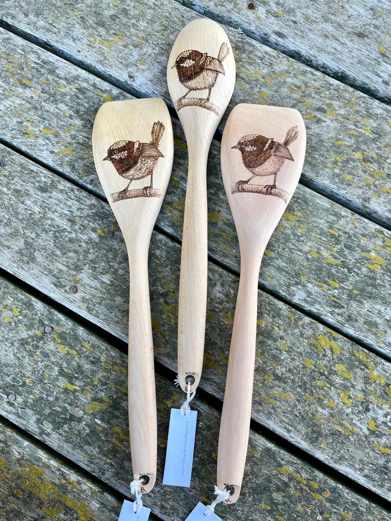 May include: Three wooden spoons with a burnt design of a small bird on each. The spoons are made of light wood and have a natural finish.