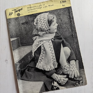 May include: Vintage black and white image of a knitting pattern booklet. The cover features a child wearing a knitted hat, scarf, and gloves. The booklet is titled "Dunraven 4 ply or Leemont Crepe 3 ply Wool" and includes the Lee Target logo.