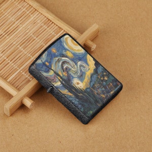 Könnte beinhalten: Ein schwarzer Feuerzeug mit einer strukturierten Oberfläche und einem aufgedruckten Bild von Vincent van Goghs Gemälde "Sternennacht".