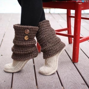 Puede incluir: Calentadores de piernas de ganchillo marrón oscuro con botones de madera, combinados con cubiertas de pie de ganchillo color crema. Una silla roja y una cubierta de madera en el fondo. Accesorio acogedor.