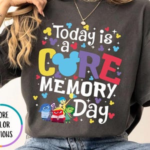 May include: A gray t-shirt with a colorful graphic that says "Today is a CORE MEMORY Day" with a Mickey Mouse head in the middle of the word "CORE". The graphic also includes the characters from the movie Inside Out.