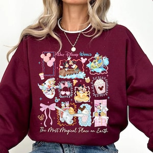 May include: Maroon sweatshirt featuring a colorful graphic of Disney World characters and attractions. The design includes Mickey Mouse, Dumbo, and other iconic elements. Text on the sweatshirt reads "Walt Disney World" and "The Most Magical Place on Earth."